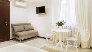 A modern room with a sofa, a dining table with chairs, a TV mounted on the wall, and a window with curtains. - Apart Hotel Quartet (Odesa)