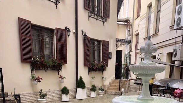 A courtyard with a central fountain, potted plants, and a building with shutters and balconies. - Apart Hotel Quartet (Odesa)