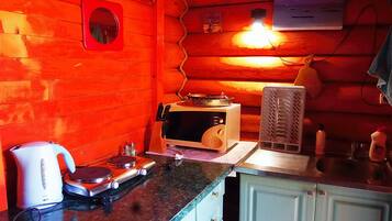 A compact kitchen with a microwave, kettle, and a small stove.