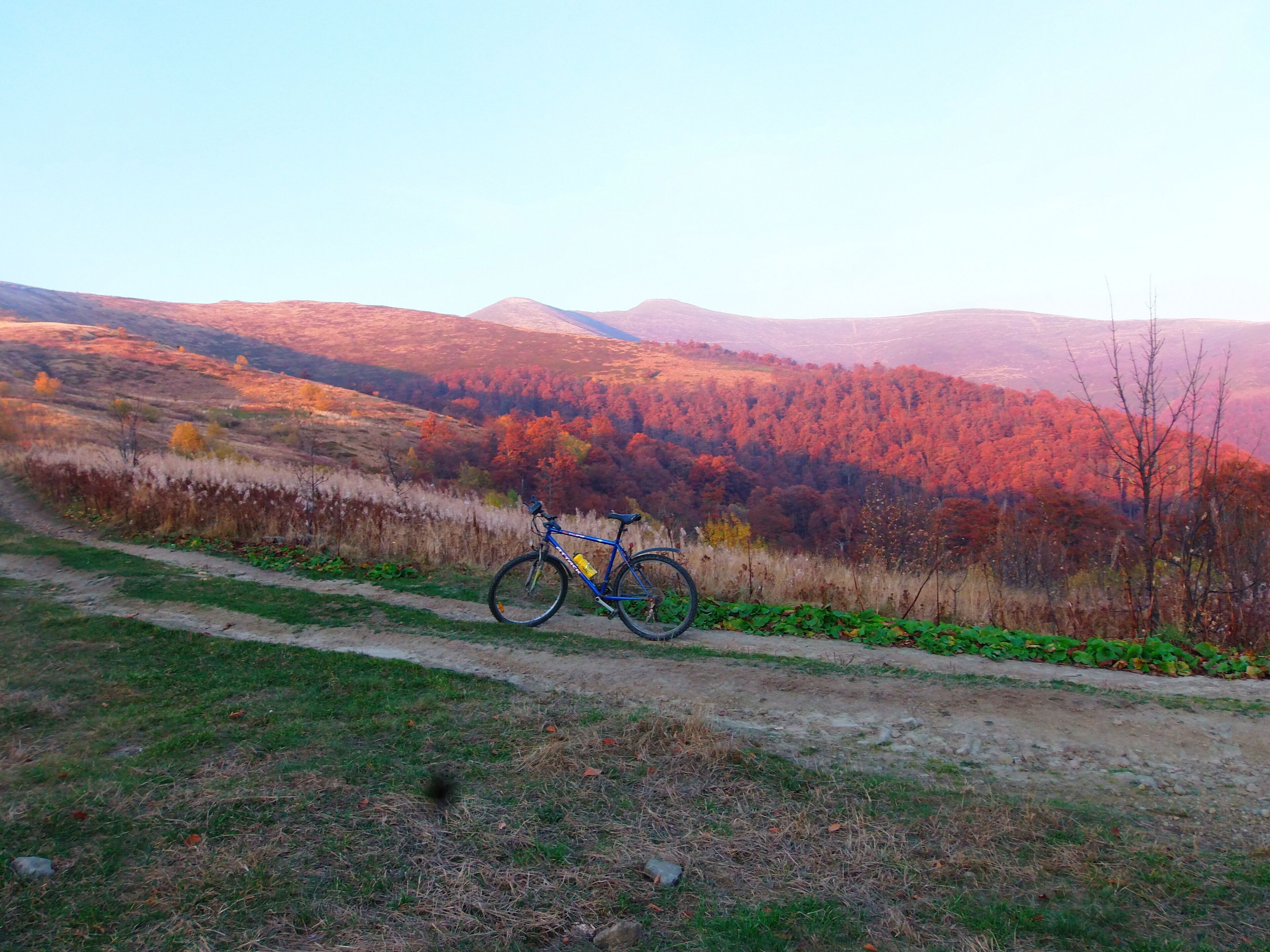 A mountain landscape with a bicycle parked on a dirt path.