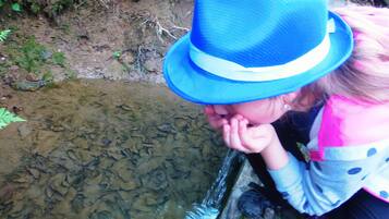 Una persona con sombrero azul y prenda con estampado de lunares cerca de un cuerpo de agua.