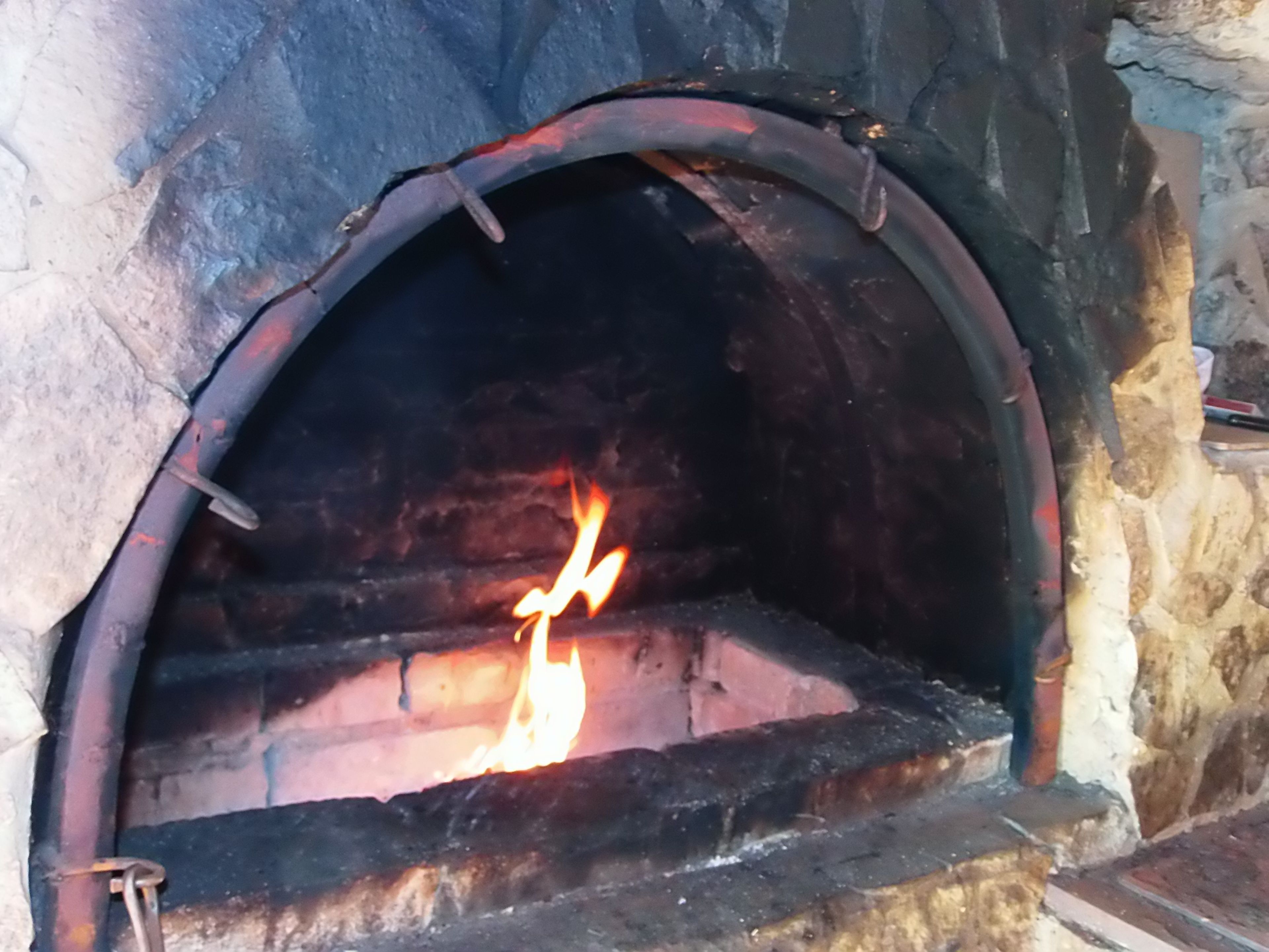 Une cheminée en pierre dans laquelle brûle un feu.