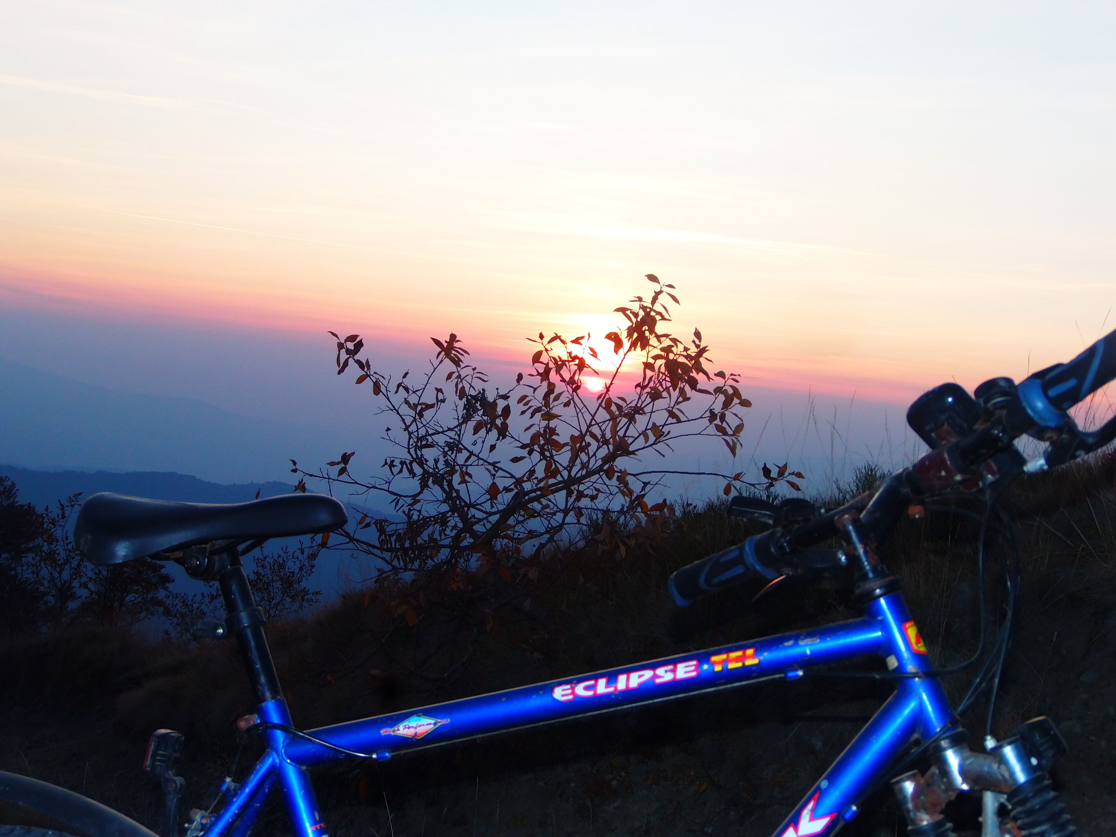 A bicycle with a blue frame and the word "Eclipse" on it, parked outdoors with a sunset in the background.