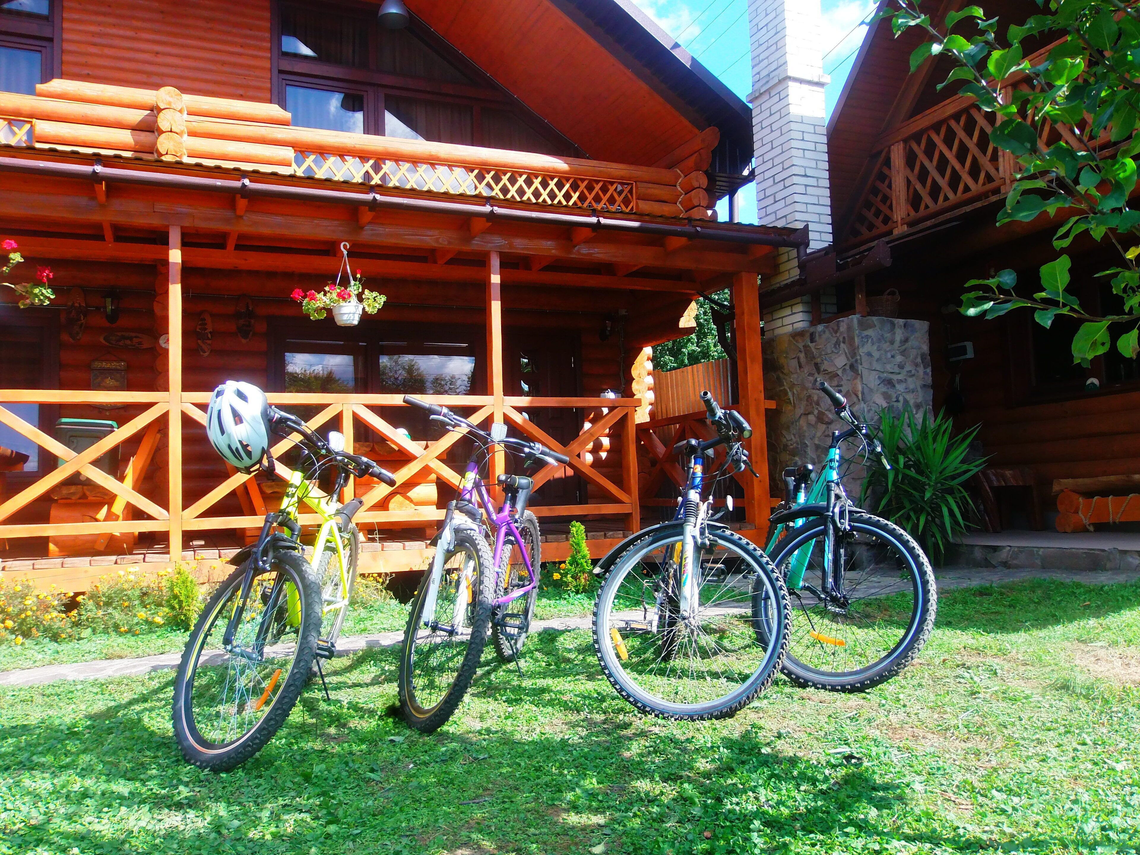 Um edifício de madeira com varanda e bicicletas estacionadas na frente.