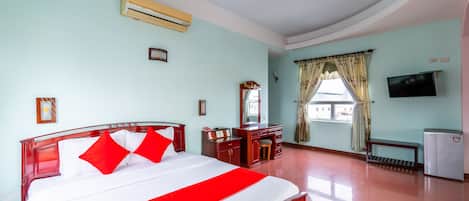 A hotel room with a bed, a desk, a television, and a window with curtains.