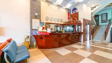 A reception area with a checkered floor, a reception desk, a blue chair, and a staircase.