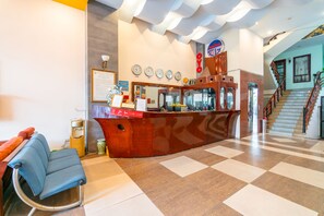 A reception area with a checkered floor, a reception desk, a blue chair, and a staircase. - Super OYO 266 Golden Gate (Da Nang)