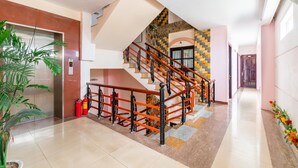 Un vestíbulo moderno de hotel con una escalera, un extintor y una planta en maceta.