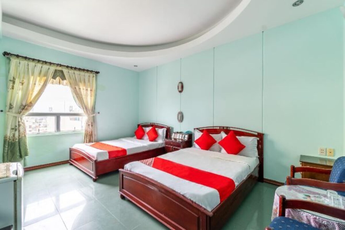 A hotel room with two single beds and one double bed, all with wooden frames and red bedding.