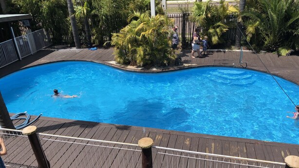 Une piscine dotée d’une terrasse en bois et d’une rambarde en métal.