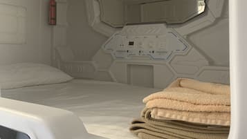 Una habitación futurista con una cama, un panel de control y un extintor.