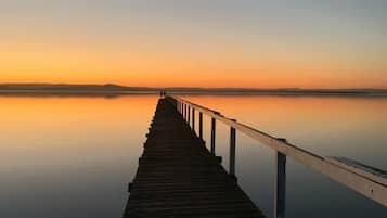 A wooden pier extending into calm water during sunset.