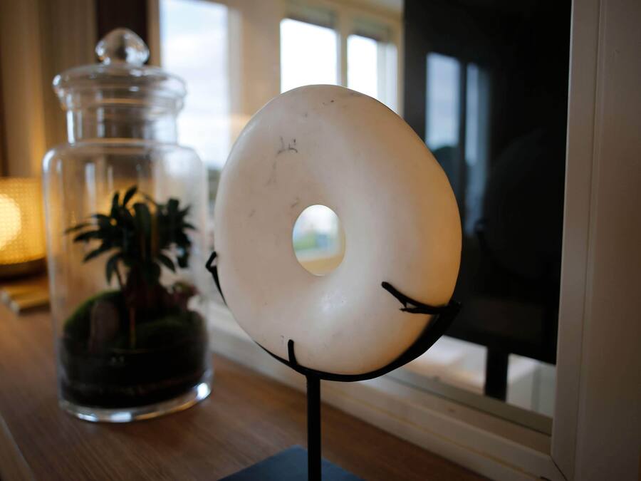 A donut-shaped object on a stand next to a glass jar with a plant inside.