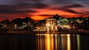 Un hôtel situé au bord de l’eau, avec un bâtiment imposant doté de nombreux balcons et d’une façade bien éclairée.