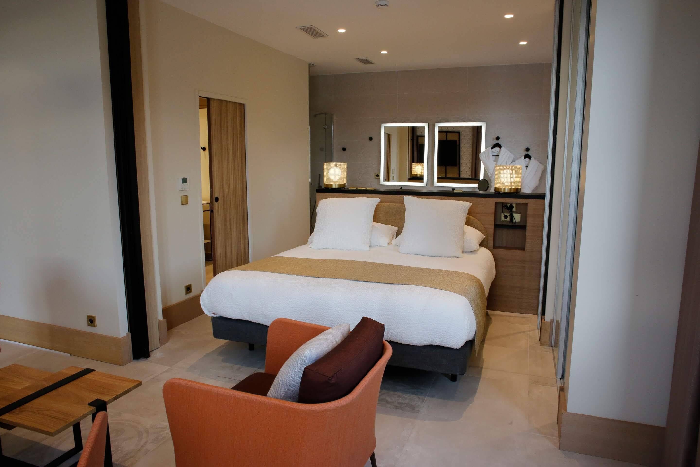 Une chambre d’hôtel avec un lit, une chaise, une table et un miroir.
