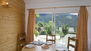 Ein Essbereich mit Holzvertäfelung, einem für vier Personen gedeckten Tisch und Blick auf eine Berglandschaft durch große Glasüren.