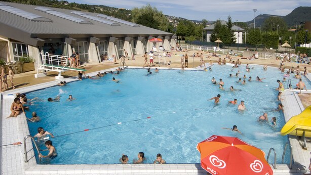 Ein großes Hallenbad mit mehreren Bahnen, einem Sprungturm und einem Rettungsschwimmerstand.
