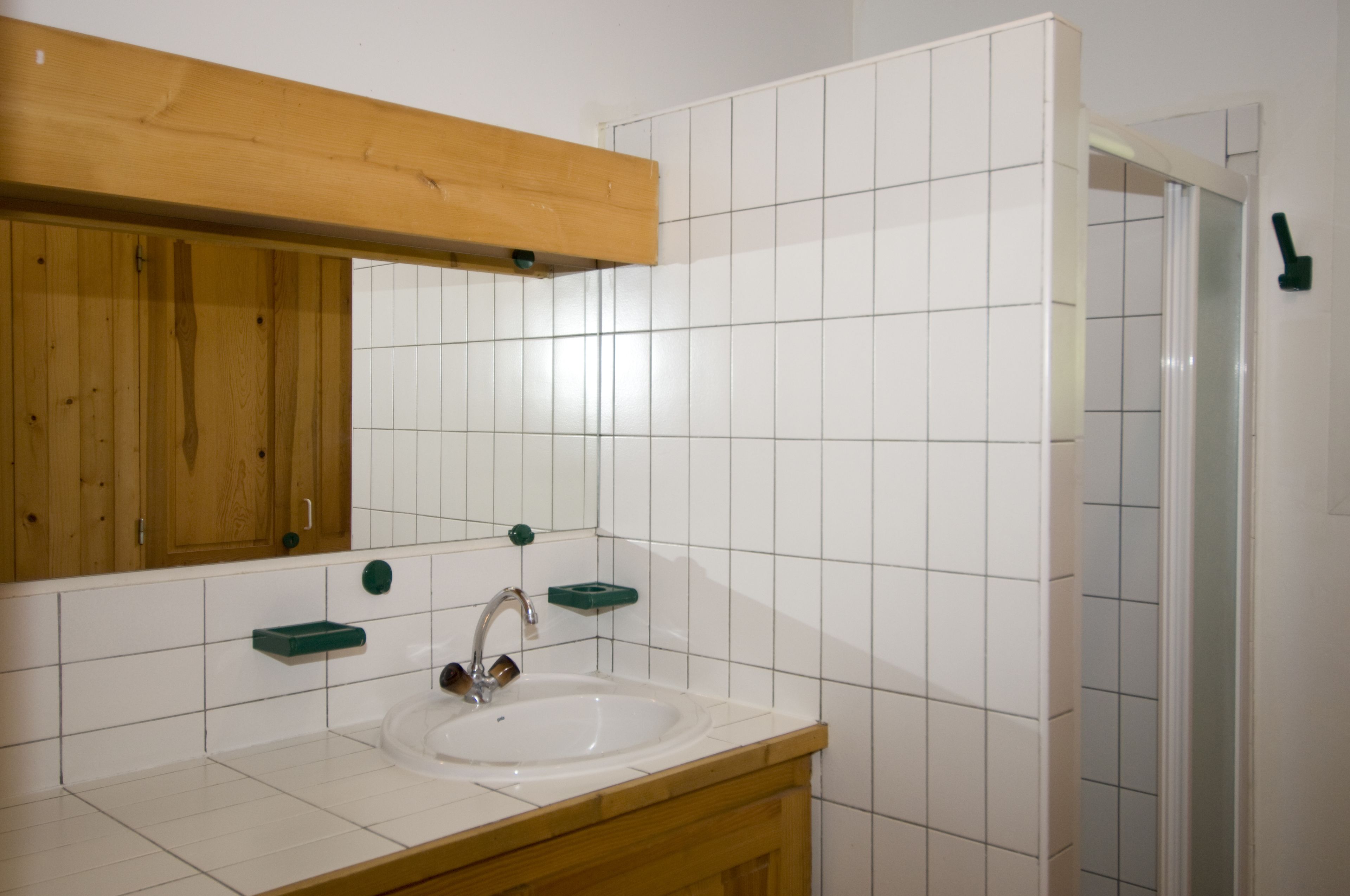 Une salle de bain avec un meuble-lavabo en bois, un lavabo blanc et un miroir au-dessus.