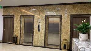 A lobby with three elevators, a marble floor, and a potted plant. - Hotel Emma (Bai Chay)