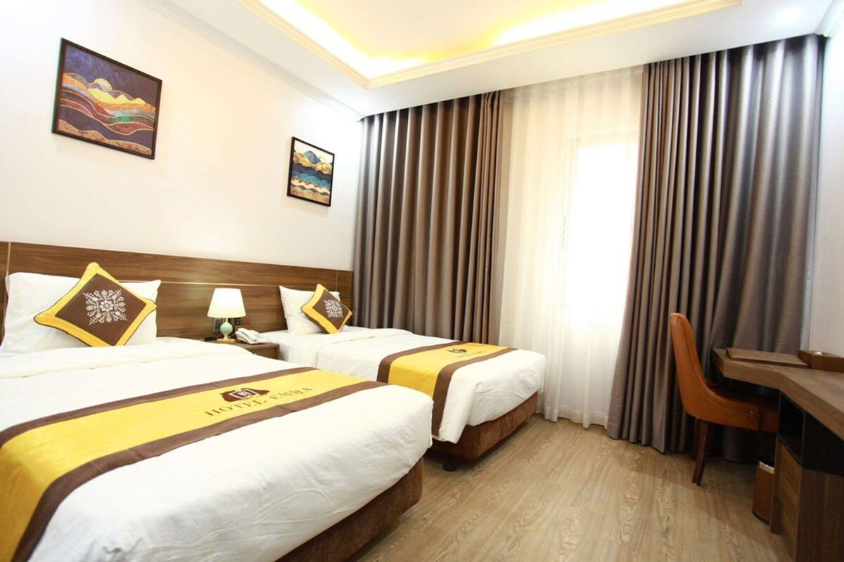 A hotel room with two beds, a desk, and a chair.