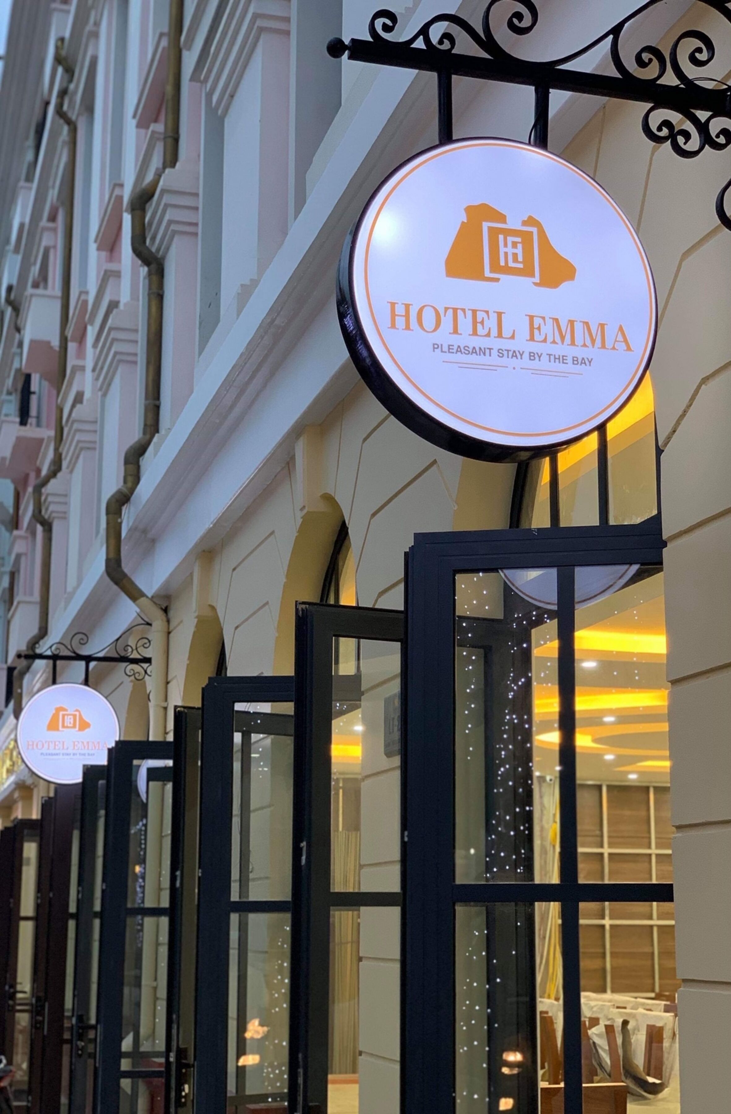 A hotel sign with the name "HOTEL EMMA" and the tagline "PLEASANT STAY BY THE BAY".