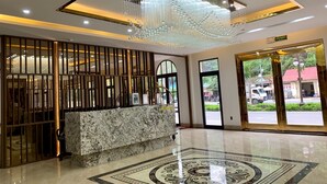 A lobby with a reception desk, a decorative chandelier, and a patterned floor. - Hotel Emma (Bai Chay)
