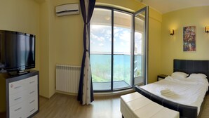 A bedroom with a large window, a bed, a TV, a dresser, and a radiator. - Apart holiday Athena Mamaia (Constanta)