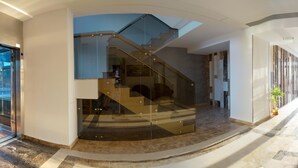 A spacious lobby with a marble floor, a glass staircase, and a seating area with leather chairs. - Apart holiday Athena Mamaia (Constanta)
