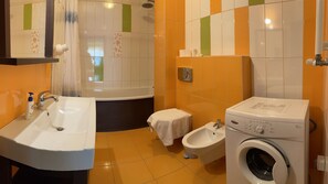 A bathroom with a sink, toilet, bidet, bathtub, and a washing machine.