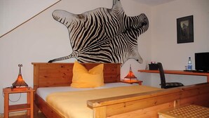 Et soveværelse med en træseng, et vægmaleri med zebraer, et skrivebord, en stol og et fjernsyn.
