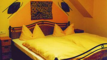 A bedroom with a bed, pillows, a nightstand, a red rug, and a wall with a geometric pattern.