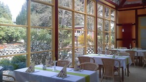 En restaurant med dækkede borde, store vinduer og udsigt til det fri.