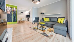A modern living room with a grey sofa, yellow cushions, a coffee table, and a patterned rug.