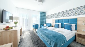 A modern hotel room with a large bed, a desk, a chair, and a bathroom with a shower.