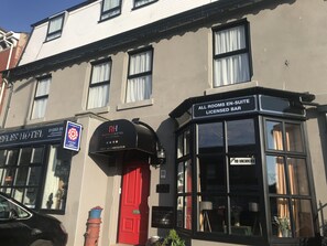 A hotel with a black mailbox, a red door, and a sign for a licensed bar.