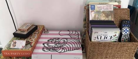 A display of board games, a PS4 console, and a basket of DVDs.