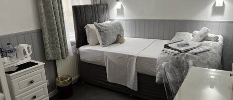 Una habitación de hotel con cama, mesita de noche, lámpara y un cuadro en la pared.
