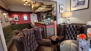 Zona de bar con asientos de cuero, una barra con aperitivos y una pared con estampado rojo.