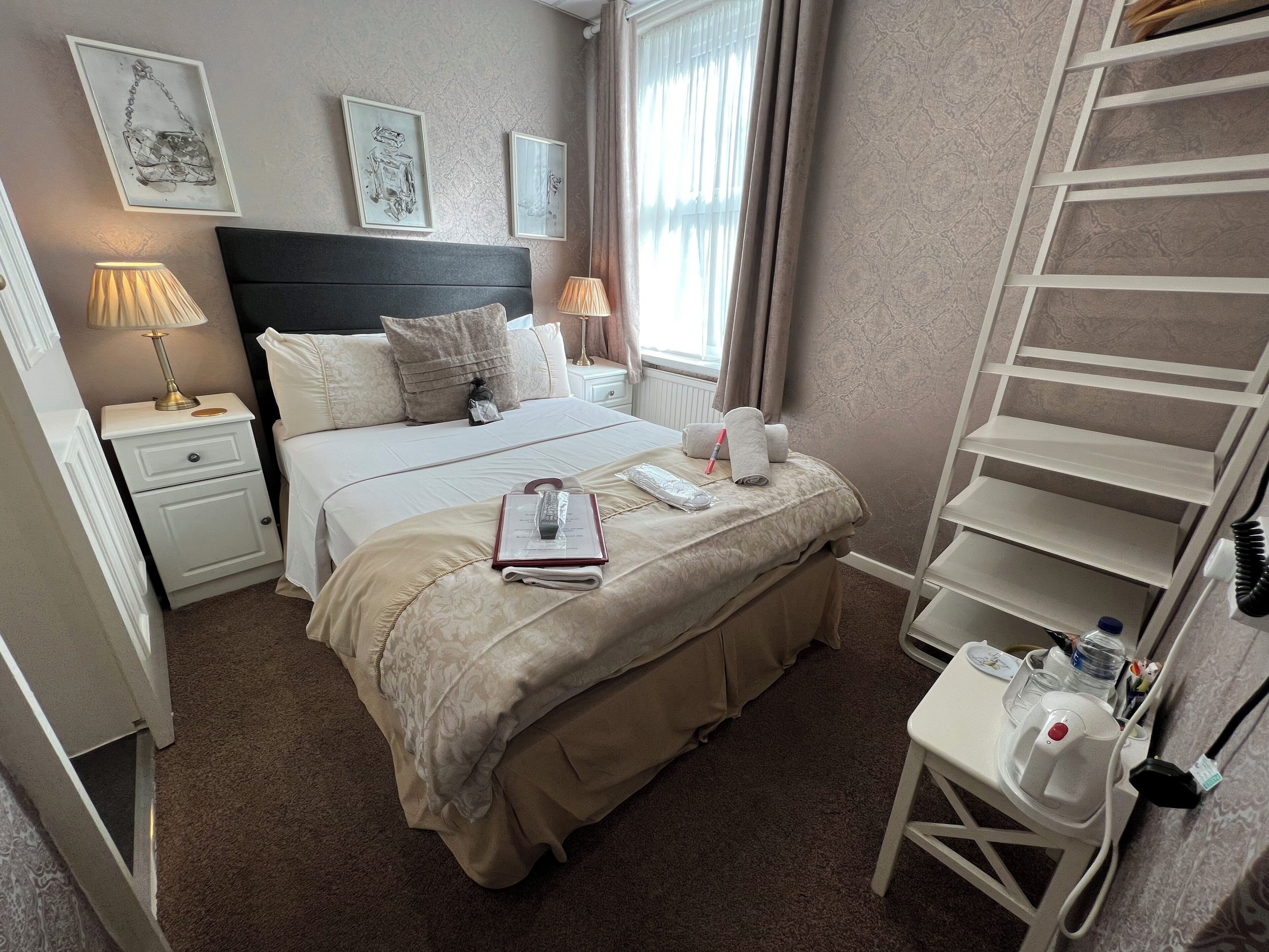 A hotel room with a bed, bedside tables, a desk, and a chair.
