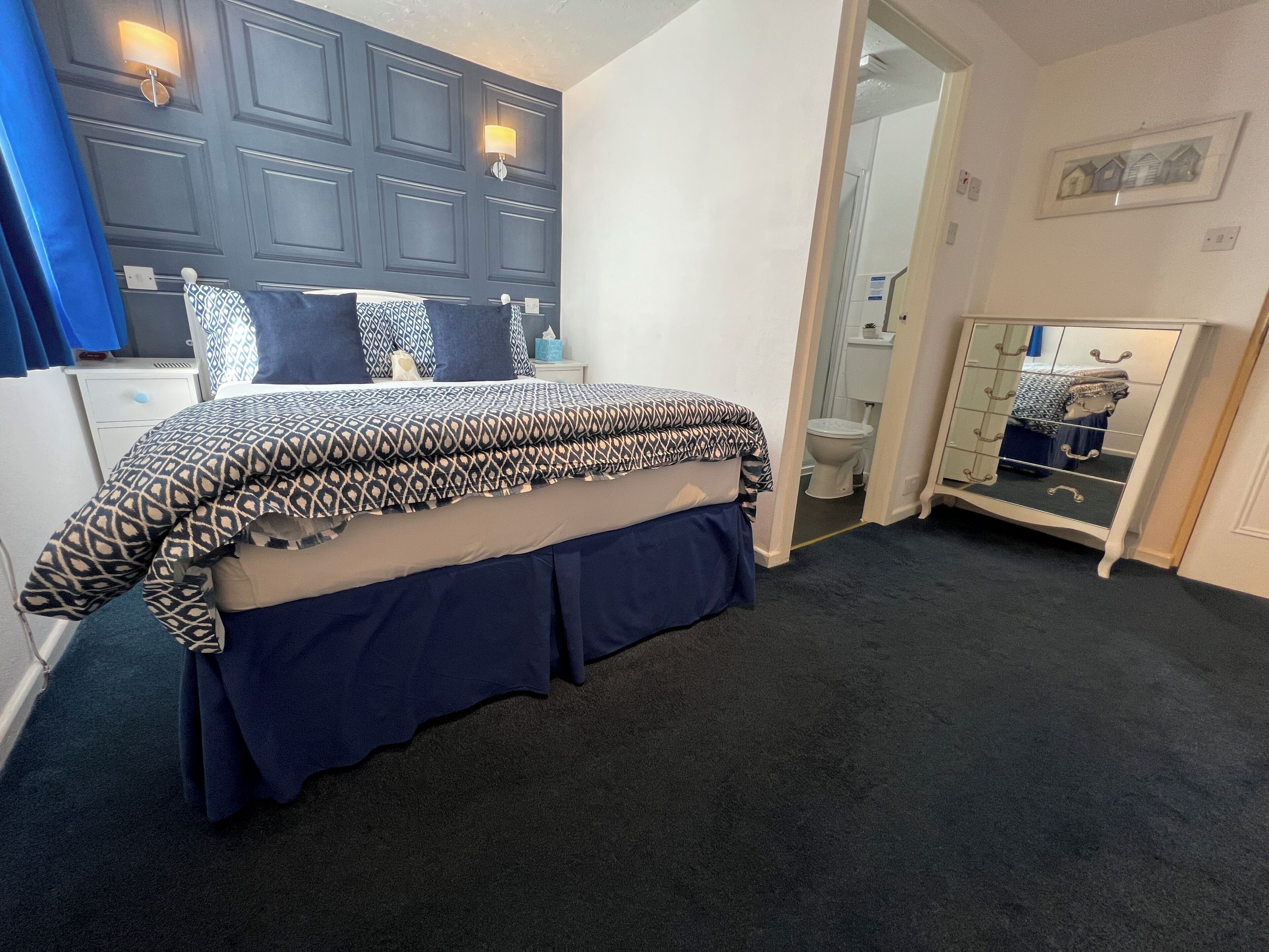 Ein Schlafzimmer mit einem Bett, einem Schminktisch, einem Spiegel und einer Tür zu einem Badezimmer.