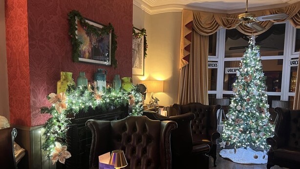 Un hall acogedor con un árbol de Navidad, sillones de cuero y una chimenea.