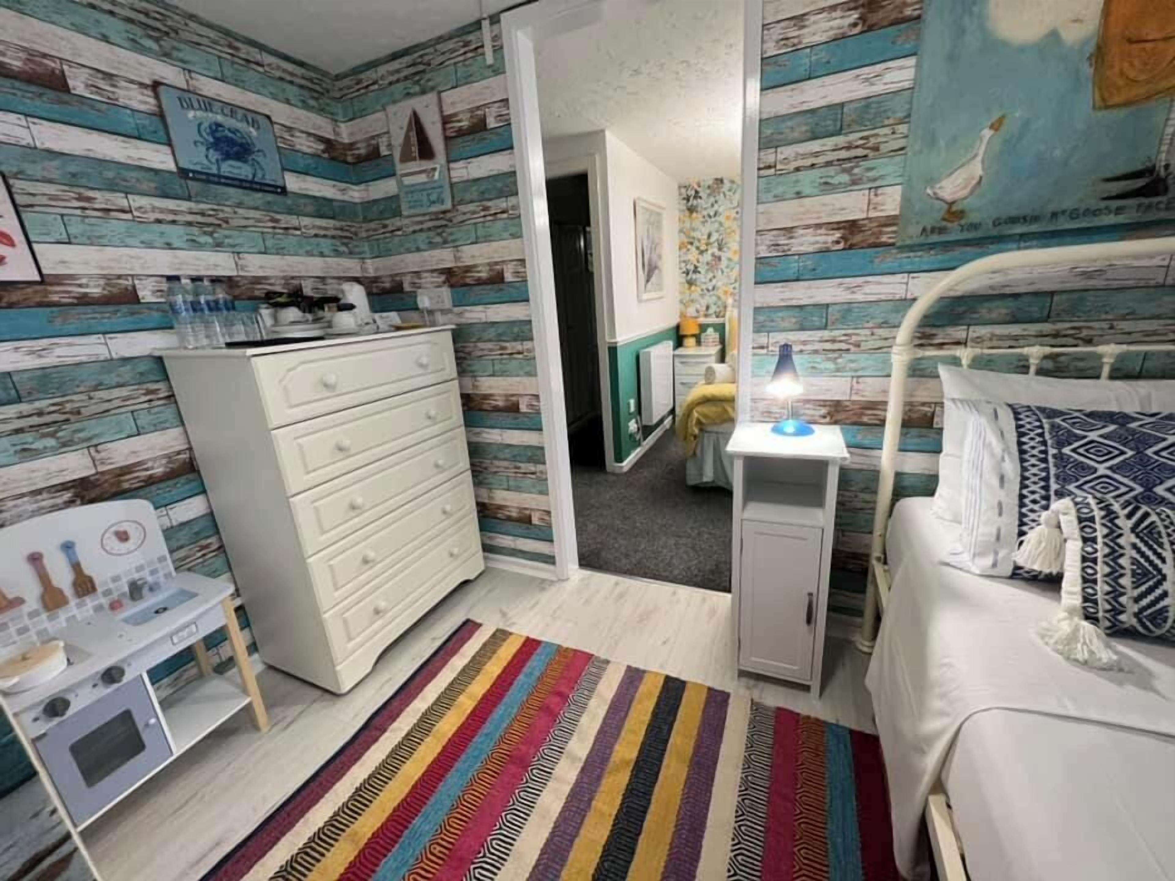 Un dormitorio con cama, escritorio, cómoda y una pequeña zona de kitchenette.