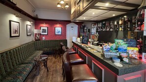 Zona de bar con mostrador, taburetes y una sala de estar con sofá y sillas.