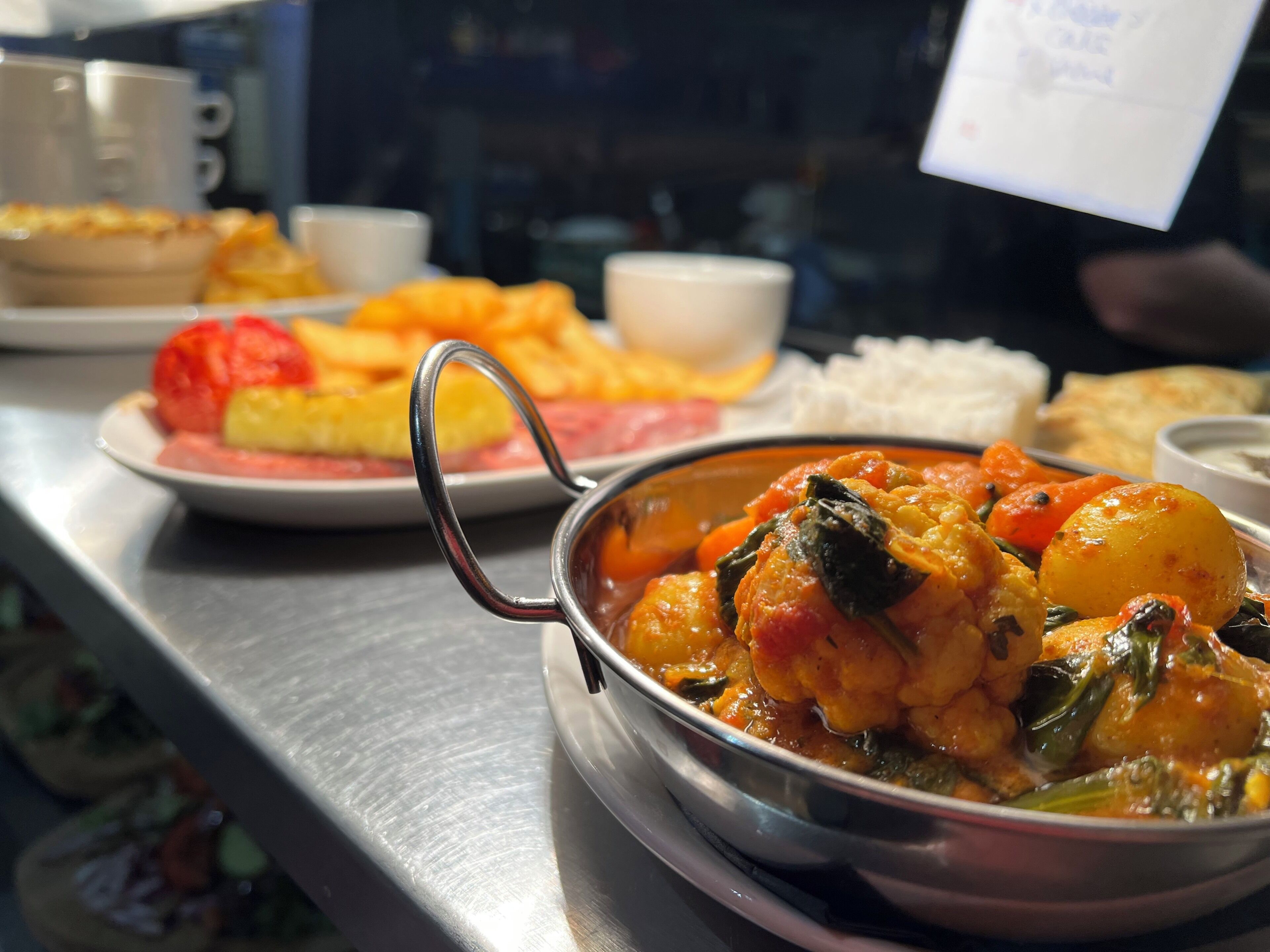 A dining table with various dishes, including a seafood stew and a plate of fries.