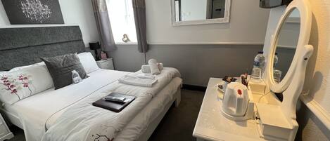 Habitación de hotel con cama, mesita de noche y espejo.