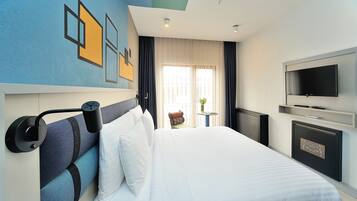 A modern hotel room with a large bed, a flat-screen TV, and a view of the city through the window.