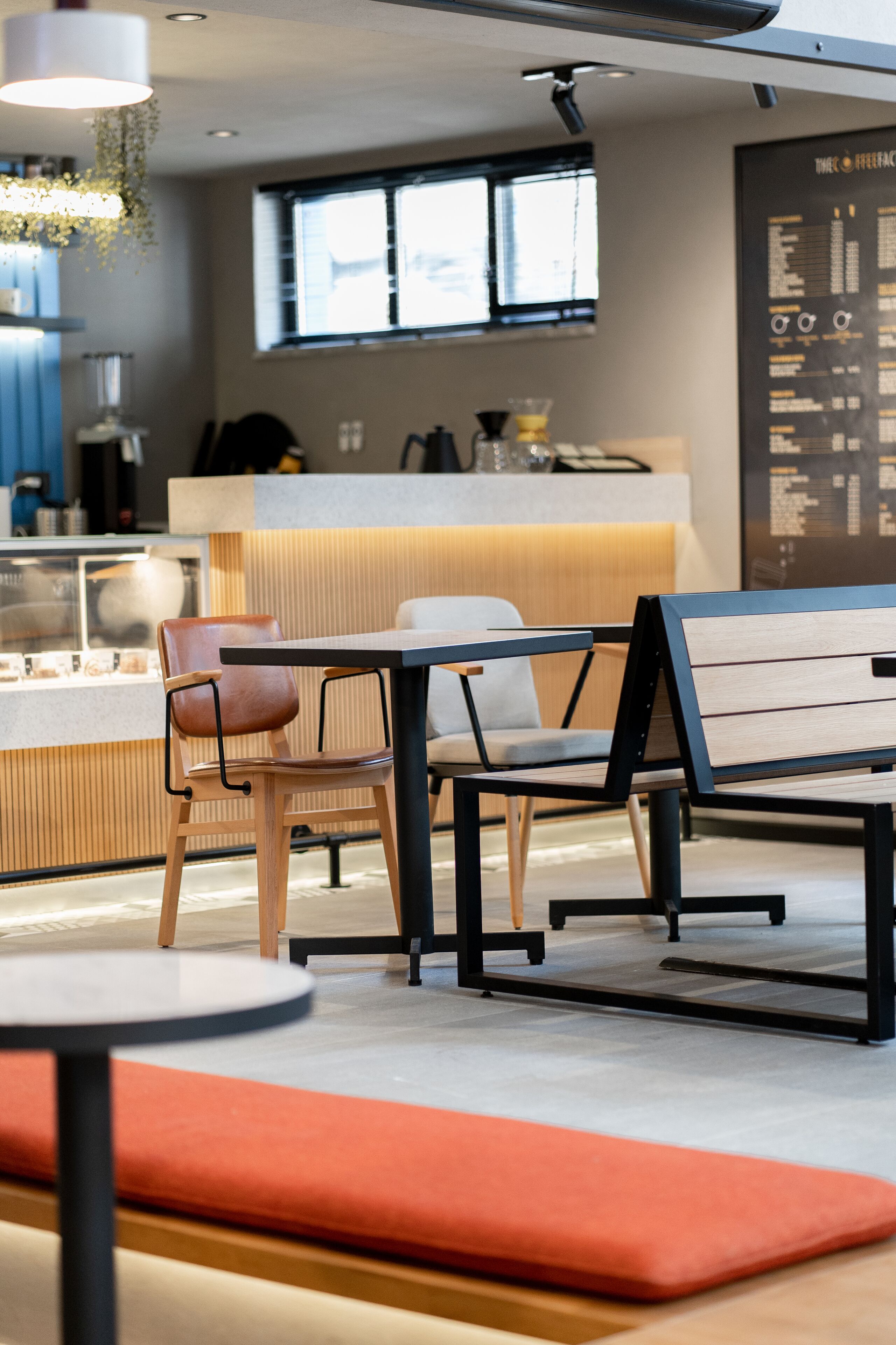 Ein modernes Café-Interieur mit einer Holzbank, einem runden Tisch und einer gepolsterten Sitzecke.