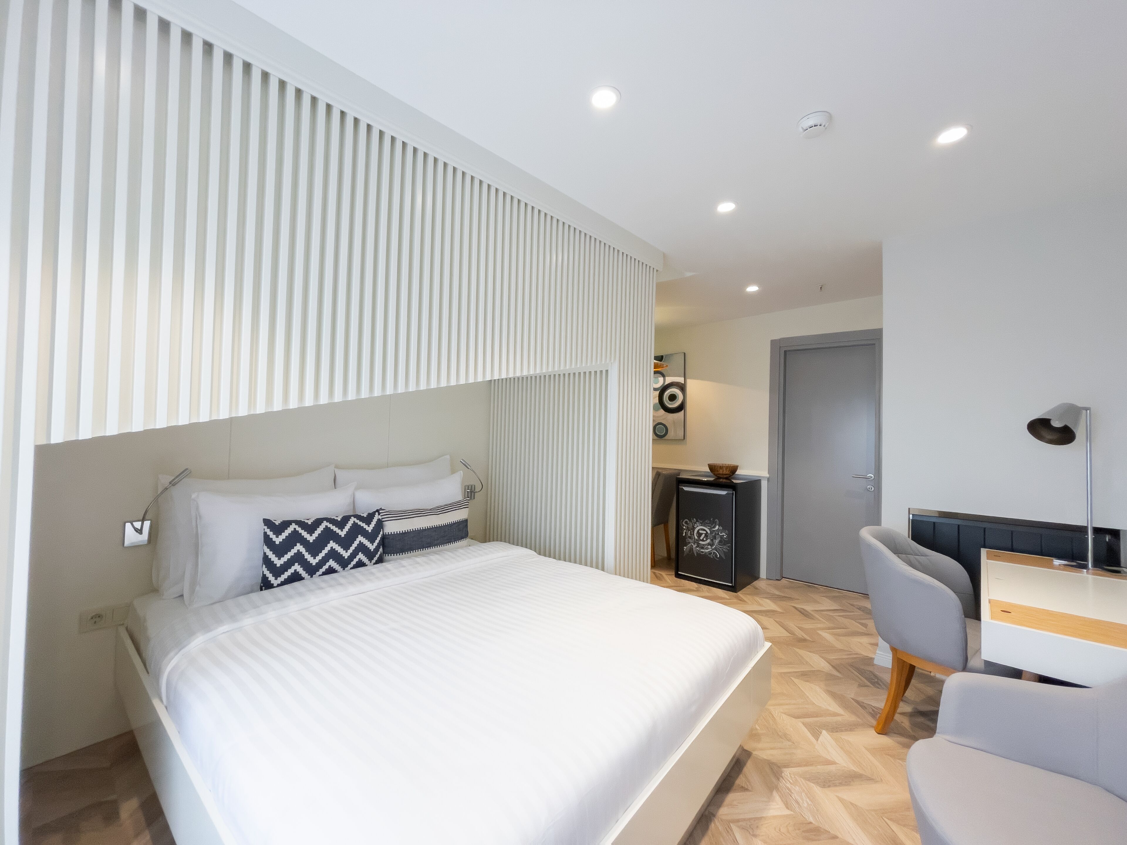 Ein modernes Hotelzimmer mit einem großen Bett, einem Schreibtisch und einem Stuhl.