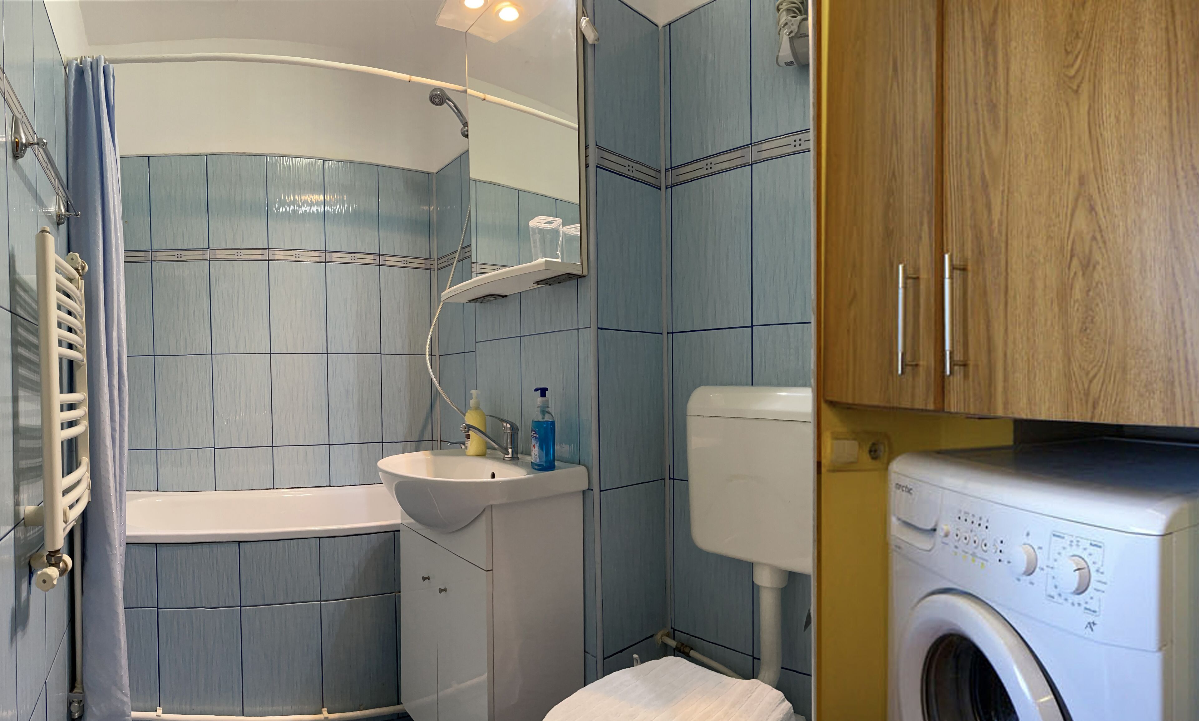 Un baño pequeño con ducha, lavabo y lavadora.