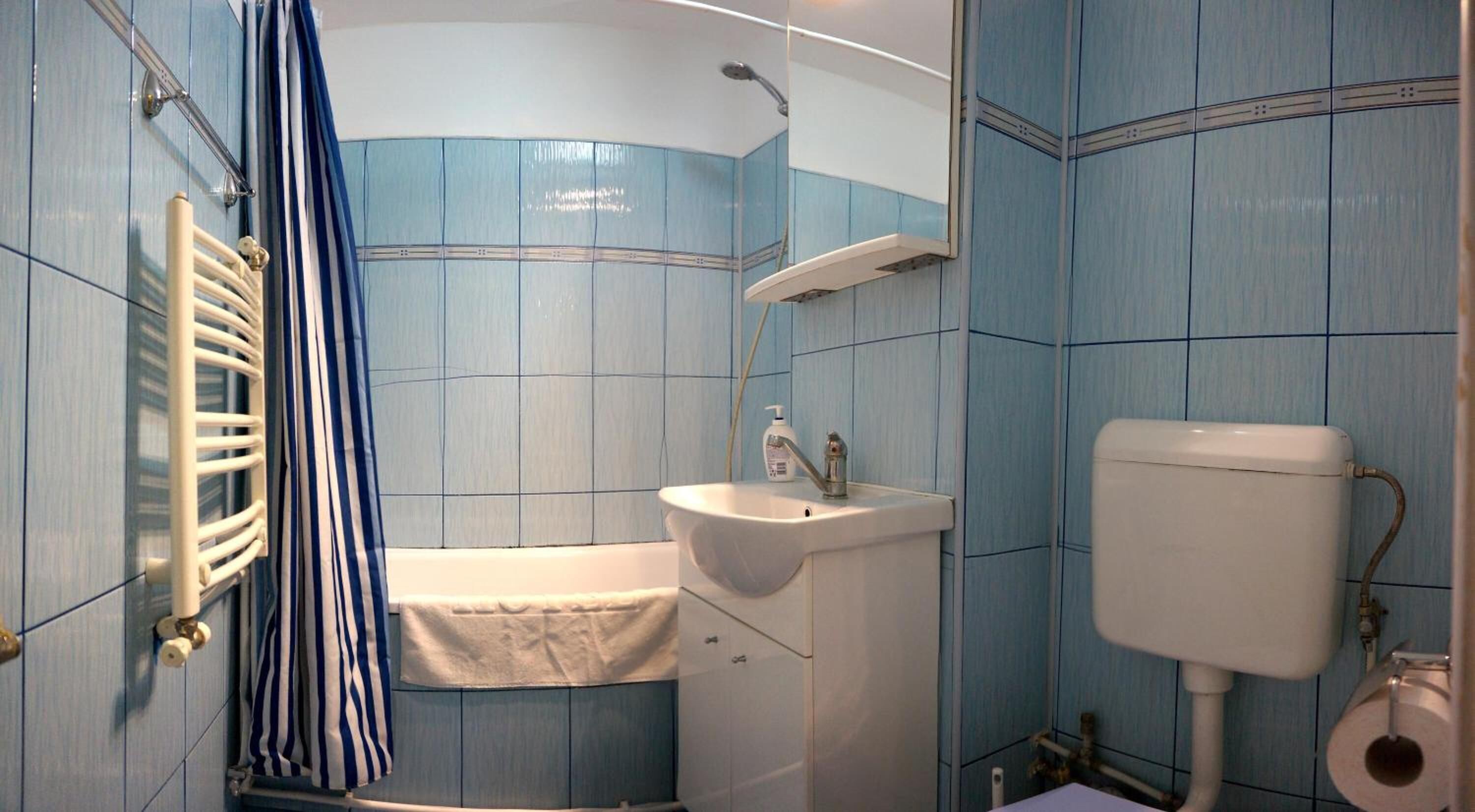 Un baño con bañera, lavamanos, inodoro y cortina de ducha.